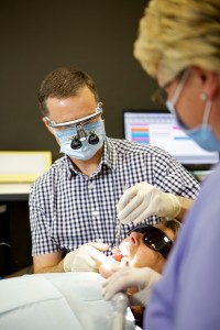 A dentist at Tony Hill Dental is performing a teeth whitening procedure on the patient